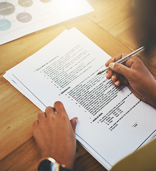 woman's hand holding a pen reviewing a document