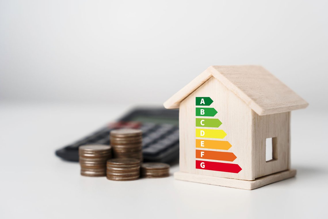 Model house with energy efficiency rating, coins and calculator representing the cost of home energy upgrades