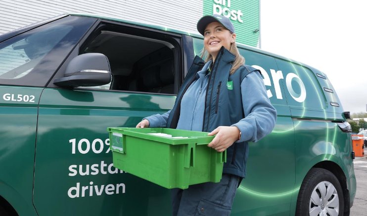 Woman in drivers seat of An Post zero emissions van with man standing beside her.