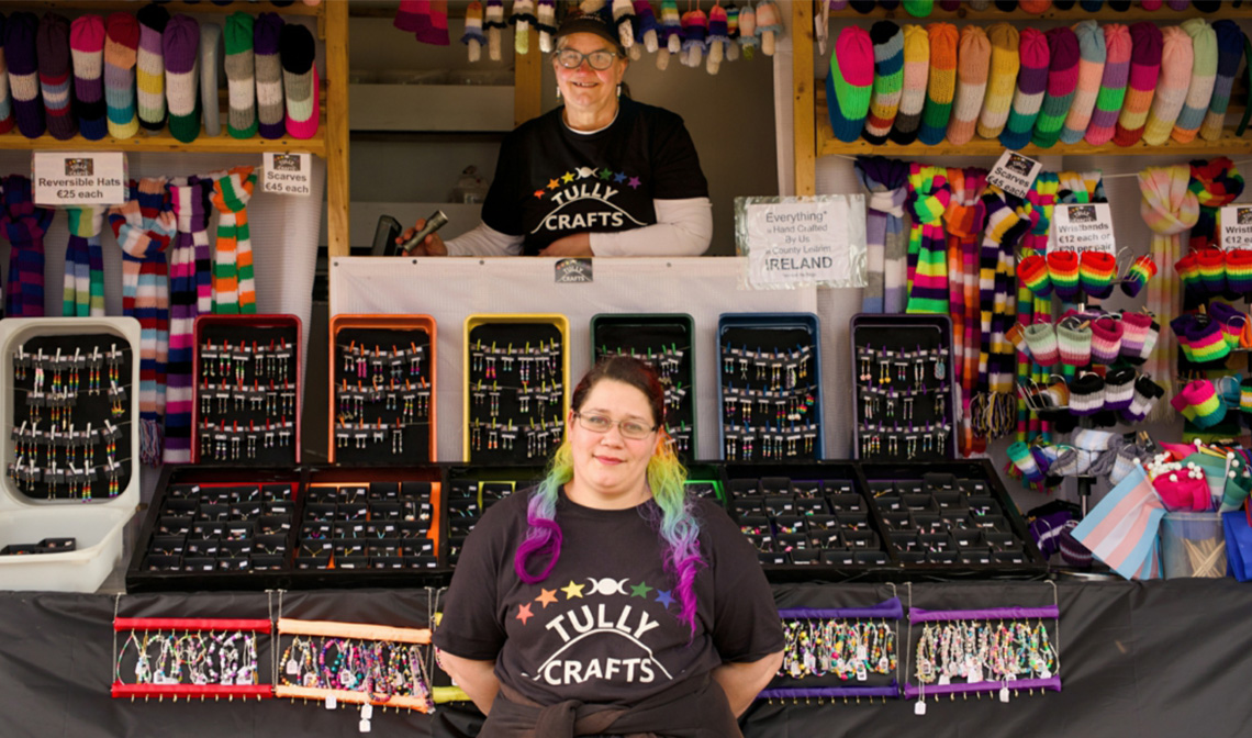Woman standing in front of a stall selling pride accessories